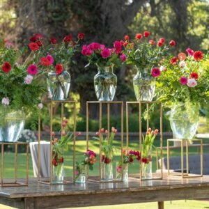 Beautiful outdoor floral arrangement with vibrant flowers on rustic table at a sunny event.