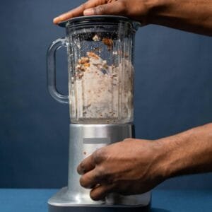 Close-up of hands preparing almond milk in a blender, showcasing a healthy lifestyle concept.