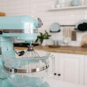A close-up of a blue stand mixer in a sleek, modern kitchen setting.
